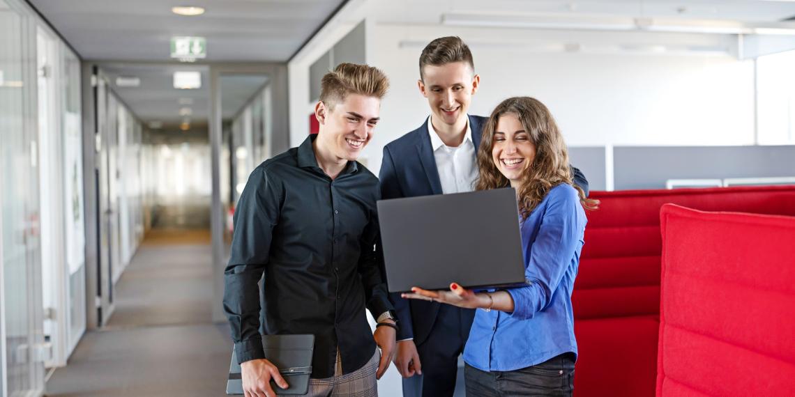 3 Trainees standing with a laptop